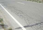 FIGURE 7.  Distress Type ACP 1 - High Severity Fatigue Cracking with Spalled Interconnected Cracks, Color photograph of asphalt concrete pavement with distress type ACP 1 - high severity fatigue cracking with spalled interconnected cracks.  The cracking is visible along the wheel path closest to the edge stripe, and its size is approximately 600 mm wide as indicated by the 500-mm scale pictured in the center of the photograph.