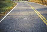 FIGURE 9.  Distress Type ACP 2 - Block Cracking with Fatigue Cracking in the Wheel Paths
Color photograph of asphalt concrete pavement with distress type ACP 2 - block cracking with fatigue cracking in the wheel paths.  The fatigue cracking is approximately 500 mm wide for the entire length of the lane in both wheel paths, and is connected to block cracking that is approximately 500 mm wide outside each wheel path and 1000 mm between the wheel paths, as indicated by the 500-mm scale pictured in the center of the photograph.