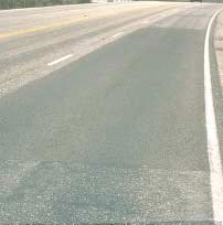 FIGURE 23.  Distress Type ACP 7 - Low Severity Patch, Color photograph of asphalt concrete pavement with distress type ACP 7 - low severity patch.  The large rectangular patch extends across one entire lane of a four-lane highway and shows no visible deterioration