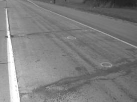  Figure 3-21:  Photographs.  Typical distress manifestations observed at MN-065-064.  This figure is comprised of two photographs labeled A and B.  Photograph A shows transverse cracking parallel to the joint along with staining and spalling.  Photograph B shows the three lanes of traffic in the project site area and no distress is visible.  