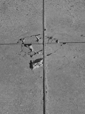 Figure 3-3 (a):  Photographs.  Typical distress manifestation observed on SD-090-019, Sections 1 and 2.  This figure is comprised of two photographs of roadway labeled A and B.  Photograph A is from section 002 and shows map cracking and spalling along the transverse joint.  The spall has come out and been repaired with an asphalt patch.  Photograph B is from section 001 and shows corner cracking and minor spalling at the intersection of the joints.