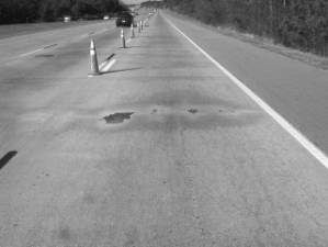  Figure 3-46 (b):  Photographs.  Typical cracking pattern at NC-444-015.  Note distress over entire slab length with spalling occurring at joints.  This figure is comprised of two photographs labeled A and B.  Photograph A shows a section of roadway from the project site where map cracking is visible.  Photograph B also shows a section of roadway from the project site.  In this photo, transverse cracking and spalling are visible.  The spalling was repaired with an asphalt patch.