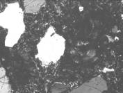  Figure 3-52 (c):  Photographs.  Petrographic micrograph of ettringite and "ASR gel blob" from spall obtained from NC-440-015.  The term ASR gel is misleading in this example, since the reaction product is slightly birefringent and, therefore, crystalline.  This figure is comprised of three micrographs labeled A, B, and C.  Photograph A uses a transmitted plane polarized light.  A large gel "blob" is seen near the right side of the micrograph.  An ettringite filled air void can be seen towards the left side of the micrograph and appears in almost an oval shape.  Photograph B is in epifluorescent mode.  The gel blob and air void can be seen in this micrograph as well.  However, the blob appears darker with some bright cracks running through it.  The air void also appears as a dark spot in the paste.  Photograph C uses a transmitted cross polarized light.  Neither the gel blob or the air void are visible in this picture.  