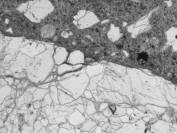  Figure 3-54 (a):  Photographs.  Petrographic micrograph of ASR gel in crack within coarse aggregate.  This figure is comprised of three micrographs, each one taken using a different light.  The micrographs show the interface between an aggregate particle and the surrounding paste.  A crack can be seen running along the interface.  This is most evident in the micrograph taken using the epifluorescent mode, where the aggregate appears black and the gel appears bright white.  Note that the gel deposit image was analyzed with the scanning electron microscope and the ASR "gel" in these images was found to be birefringent and crystalline. 