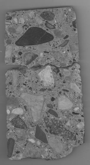  Figure 3-9 (a):  Photographs.  Slab 1B stained with sodium cobaltinitrite/rhodamine B from SD-090-019-001.  This figure is comprised of two photographs of slab 1B labeled A and B.  The slab was stained with sodium cobaltinitrite/rhodamine B.  Photograph A is a picture of the entire stained slab.  A large crack is visible approximately half way down the slab.  Photograph B is a stereo optical micrograph of a reactive rhyolite particle.  The particle has a crack running it and reactive materials are visible in the paste surrounding the particle.  The figure also contains a table listing the litho types, their volume in milliliters and their volume as a percent of total volume.  Volume was determined by water displacement from a sample gathered at a nearby river.  The total volume of all of the lithos was 1,479 milliliters.  The information in the table is as follows: