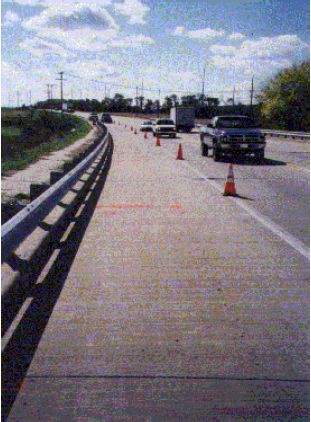 The figure consists of two photographs; one shows the site looking north, the other looking south. The site is a concrete pavement on the shoulder of the highway.
