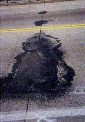 The figure consists of a photograph of asphalt patching on a concrete pavement along a transverse joint in the travel lane.