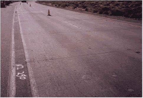 In the photograph, two lanes and a shoulder are visible and the station designation parenthesis M2 Station 250) is written on the pavement shoulder.