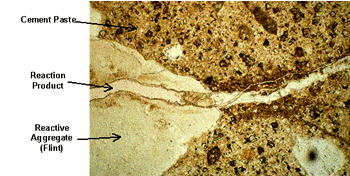 Figure 6. Enlarged Photo. Thin-Section Cut of ASR-Damaged Concrete, Showing ASR Gel and Typical Crack Pattern (Through Aggregate and into Surrounding Matrix). This photo shows cement paste, a particle of reactive aggregate (in this case, flint), and a ribbon of reaction product (alkali-silica reaction gel) running through both of them. A crack runs from a point where the gel meets the cement paste and continues parallel to the gel.