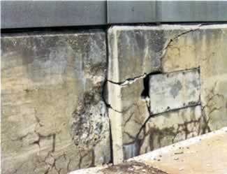 Figure 9. Photo. Misalignment of Adjacent Sections of a Parapet Wall on a Highway Bridge Due to ASR-Induced Expansion (SHRP-315, 1994). This figure shows the misalignment of adjacent sections of a parapet wall on a highway bridge. Although there is no scale, the lateral misalignment could be on the order of several centimeters. Both sections contain horizontal and vertical cracks