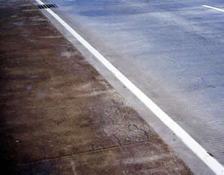 Figure 28. Photo. Comparison of Existing ASR-Affected Concrete (at left) with New Overlay Concrete (at right). The ASR-affected concrete shows some cracking, primarily near the edge of the pavement, but the new overlay concrete is not cracked.