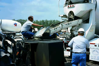 Figure 30. Photo. Utility Transmission Tower Footing in Corpus Christi, TX. This photo shows two workers pouring concrete.