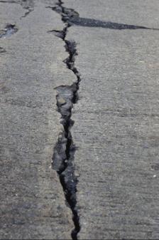 Figure 59.  Photo.  Photograph of deflection spalling on a CRCP.  Large, deep cracks (in this case caused by heavy aircraft loads) show the severity of deflection spalling.