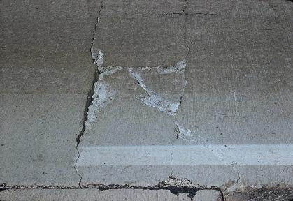 Figure 64.  Photo.  Typical CRCP punchout distress.  A rectangular piece of slab, formed by longitudinal crack joining two closely spaced transverse cracks, shows the punchout distress, made more severe by a diagonal crack within the rectangular piece.