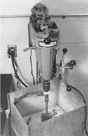 A core bit is mounted vertically under a press machine. The downward pressing of the core bit is done by way of the hand wheel attached vertically and to the side of the press for right hand operation. The hand wheel contains multiple knobs for easy grip on various points of the wheel. A water hose is connected to a water swivel above the core bit. The core bit is surrounded by a sheet-metal basin for water drainage control.