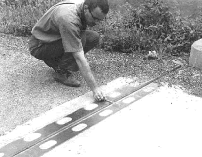 The photo shows an engineer measuring the relative positions of each side of the joint at the end of a concrete bridge deck.