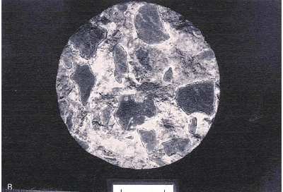 The photo shows the surface of a concrete section cored from the same slab in figure 103.  There is a dried, white deposit around each piece of aggregate.