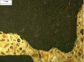 A crack is shown along the perimeter of a coarse aggregate and one also through the paste