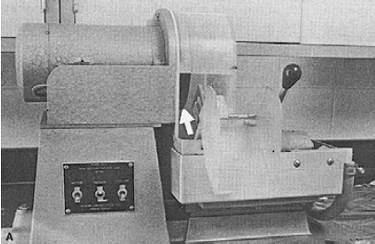 A saw machine has a very thin diamond-edged blade disk for slicing thin sections. The blade disk, pointed out by a white arrow, is mounted vertically for a forward slicing motion. 