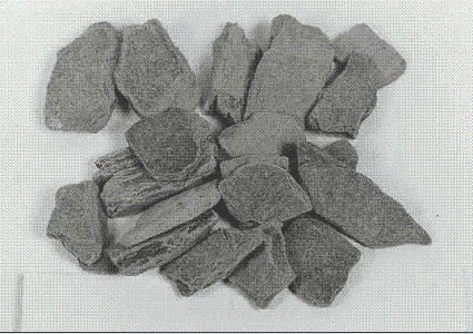 Several coarse aggregate particles of a crushed slate are shown. They are gray and rather flat and angular.