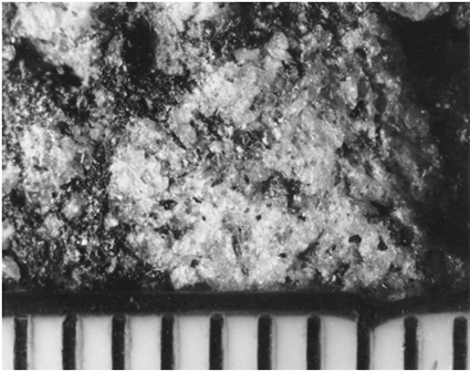 A magnified view of pavement surface centers on a 6-millimeter aggregate particle. It has zones of weakness to provide an irregular skid resistant surface. This surface is good for skid resistance