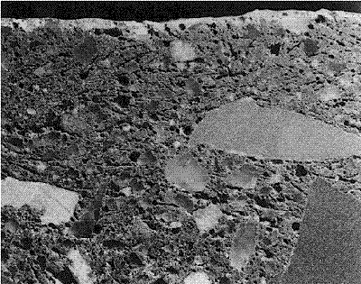 Molds of ice crystals are quite visible and generally parallel with the concrete surface. The molds, now empty, create zones of weakness throughout the concrete. Field width is 75 