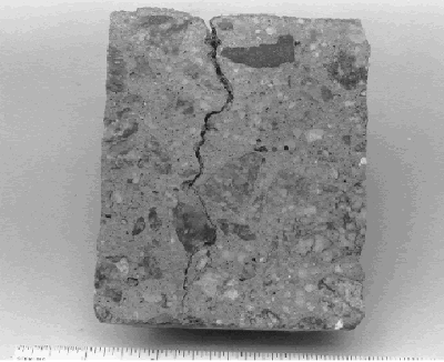 Photo shows a typical plastic shrinkage crack that is wider at the concrete surface and has an irregular shape as the crack becomes narrower toward the bottom of the vertical cross section shown