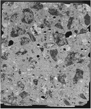 The surface of the concrete cross section shown has irregularly shaped voids. In this instance, the concrete, which had not yet been consolidated, became hard and unworkable while repairs were being made on the paving equipment. The specimen is 100 millimeters across, and some of the large voids exceed 5 millimeters in size.