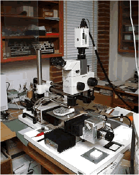The photo shows a stereoscopic microscope with a polished sample set on the stage. Either linear traverse or point count software can be used to control the motion of the stage and collect data. A video camera is also mounted on the microscope so that the image of the polished surface can be shown on a screen.