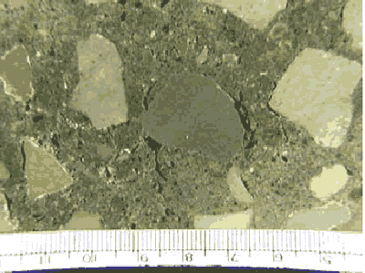 The lapped surface shown has a knot of cement (or sometimes called a ball of cement) that can be confused with coarse aggregate. Its rounded shape was caused by tumbling in the mixer