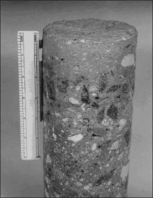 The concrete core shown has a typical 19-millimeter nominal maximum size coarse aggregate. However, the top 50 millimeter of the core is devoid of any coarse aggregate. This occurred because of rain and snow falling after the placement but before the concrete had set. The coarse aggregate sunk out of the overwatered zone leaving a top zone of mortar.