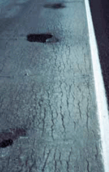 The surface of the concrete structure shown has cracks that are parallel with its length showing that the concrete has expanded transversely but not longitudinally.