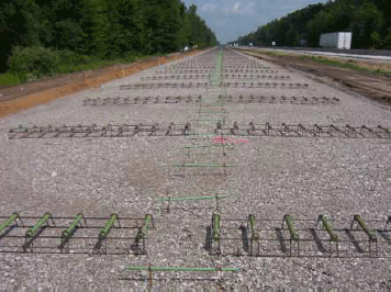 Photo. Tie bars and dowel basket placed on base. This photograph shows tie bars and dowel baskets that have been placed on the base before paving.