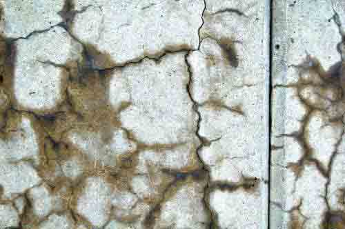 Photo. Closeup view of cracking on concrete barrier along State Route 2 near Leominster, MA. This photo shows a closeup view of the cracks in the concrete barrier; moisture surrounds the cracks and the cracks look dark brown. 