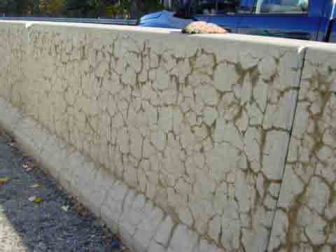 Photo. Extensive map cracking in several concrete barriers along State Highway 2 near Leominster, MA. This photo shows several horizontal cracks along two sections of concrete barriers, and the cracks are connected by several vertical cracks. 