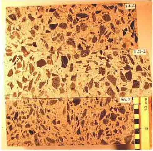 Photo. Polished surfaces of three concrete cores. The size, shape and color of the coarse aggregate particles and their distribution are shown. Photograph by Dr. P.E. Grattan-Bellew. This photo shows three concrete cores cut lengthwise. The cores are labeled, starting from the top, 10-2, T22-2, and 56-2. A metric scale is shown next to the third core sample and illustrates that the diameter of the core is near 10 centimeters wide (near 4 inches). The aggregates in the samples are clearly shown in all three samples.
