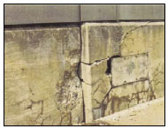 Figure 5. Photo. Misalignment of Adjacent Sections of a Parapet Wall on a Highway Bridge Due to ASR-induced Expansion. This figure shows the misalignment of adjacent sections of a parapet wall on a highway bridge. Although there is no scale, the lateral misalignment could be on the order of several centimeters. Both sections contain horizontal and vertical cracks.
