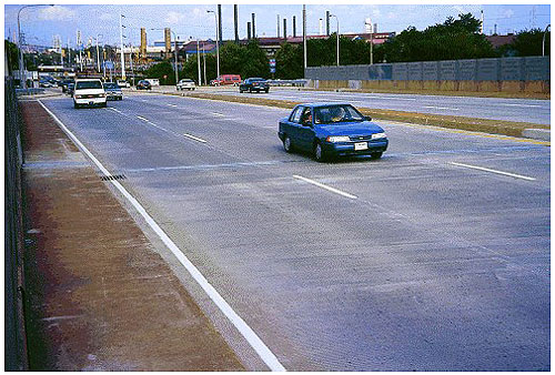 Figure 27.  Photo. Bridge Deck Overlay, Wilmington, DE. This photo shows three lanes and a shoulder of a six-lane bridge.