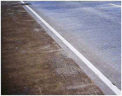 Figure 28.  Photo. Comparison of Existing ASR-Affected Concrete (at left) with New Overlay Concrete (at right).  The ASR-affected concrete shows some cracking, primarily near the edge of the pavement, but the new overlay concrete is not cracked.