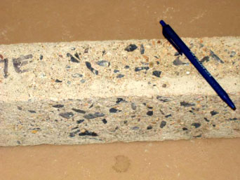 The picture shows the scaling of a concrete prism after testing. The aggregate is exposed in the surface of the prism.