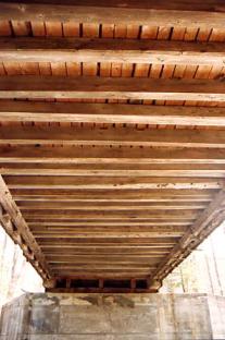 This picture shows a similar bridge underside but the horizontal floor beams are lighter and more numerous, set closer together without stringers.