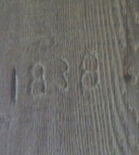 This photo shows the date 1838 carved into a wood end post. The numbers look raised, rather than carved.