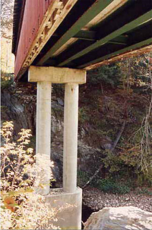 Sometimes a deck is replaced independently, but within the shell of an original bridge. The picture shows three longitudinal steel beams within but below the original trusses. The beams rest on the pier cap but do not support the timber trusses that still must carry the weight of the covering and snow.