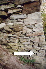 The picture shows a closeup of a bowed bridge abutment stem where the stones have cracked and shifted at the bottom from settlement of the foundation or mud sill.