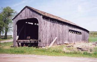 The picture shows a side view of a bridge with unfinished siding that is naturally gray and weathered.