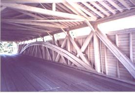 This interior shot of a Burr arch shows a heavy, double arch connected over the bridge wall diagonal trusses.