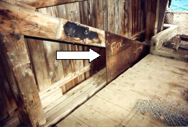 The arrow points to a triangular heel plate bolted to the end of a queenpost truss to reinforce the original timber. Such large steel surfaces often lead to condensation that rots the timber behind the plates. It is impossible to inspect the area without removing them.