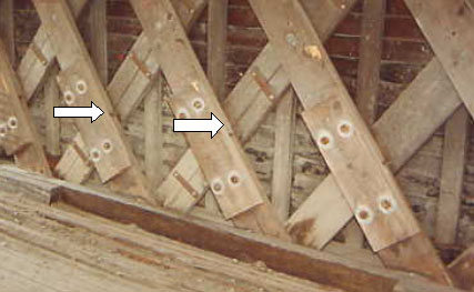 The picture shows four spliced lattice tail replacements bolted to the original lattice. The arrows point to the gaps behind the splices that indicate early signs of failure of the connection.