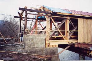 The picture shows an exterior view with the rebuilding of the bridge in process. The framing for the independent shelter panels is separate from the truss diagonals on the interior that were completed before the siding and the roof.