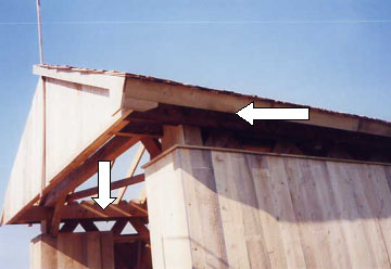 Good air circulation including open space below the eaves and above the siding prevents moisture that rots the truss members and is essential when recovering a bridge. The picture shows the two white arrows pointing to the gaps above the lattice and below the eaves between the top of the side and the underside of the top chord. An inclined top sill board on the roof also protects the tops of the vertical siding.